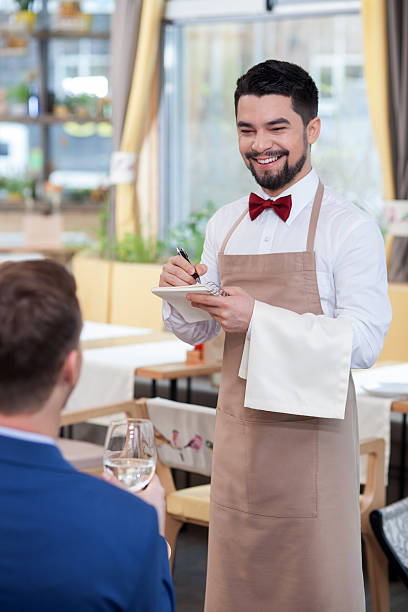 allegro giovane cameriere è servire un cliente - restaurant waiter table wait staff foto e immagini stock