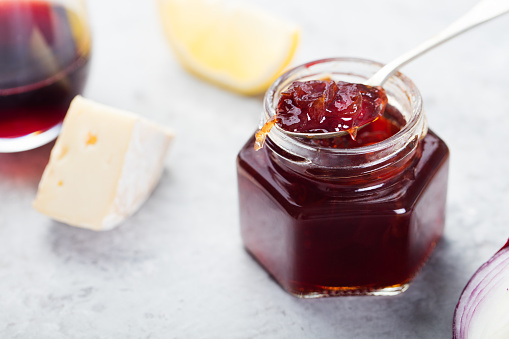 French cuisine Onion confiture, jam with lemon and piece of cheese on stone table