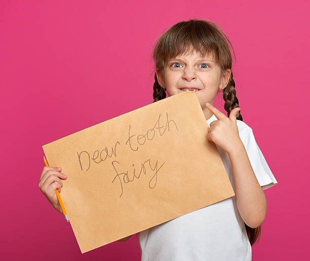 istock lost tooth girl portrait, studio shoot on pink background 501090932