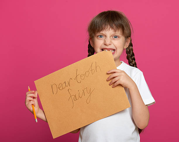 istock lost tooth girl portrait, studio shoot on pink background 501090996