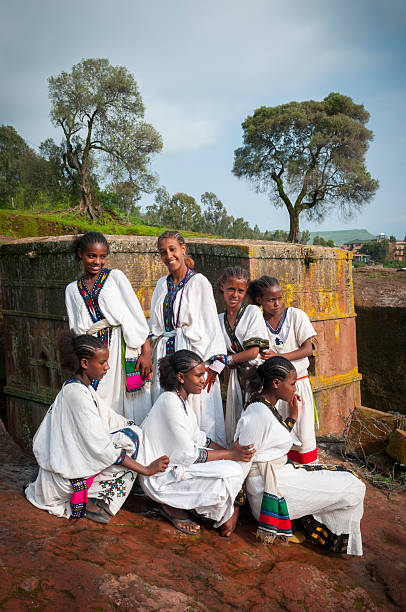 Ethiopian culture in Lalibela, Ethiopia Lalibela, Ethiopia - August 22, 2010: Seven teenage Ethiopian girls in traditional dress stand and kneel together outside the Church of St. George (Bete Giyorgis in Amharic) in Lalibela, Ethiopia. The church was built in the early 13th century. the church of saint george lalibela ethiopia stock pictures, royalty-free photos & images