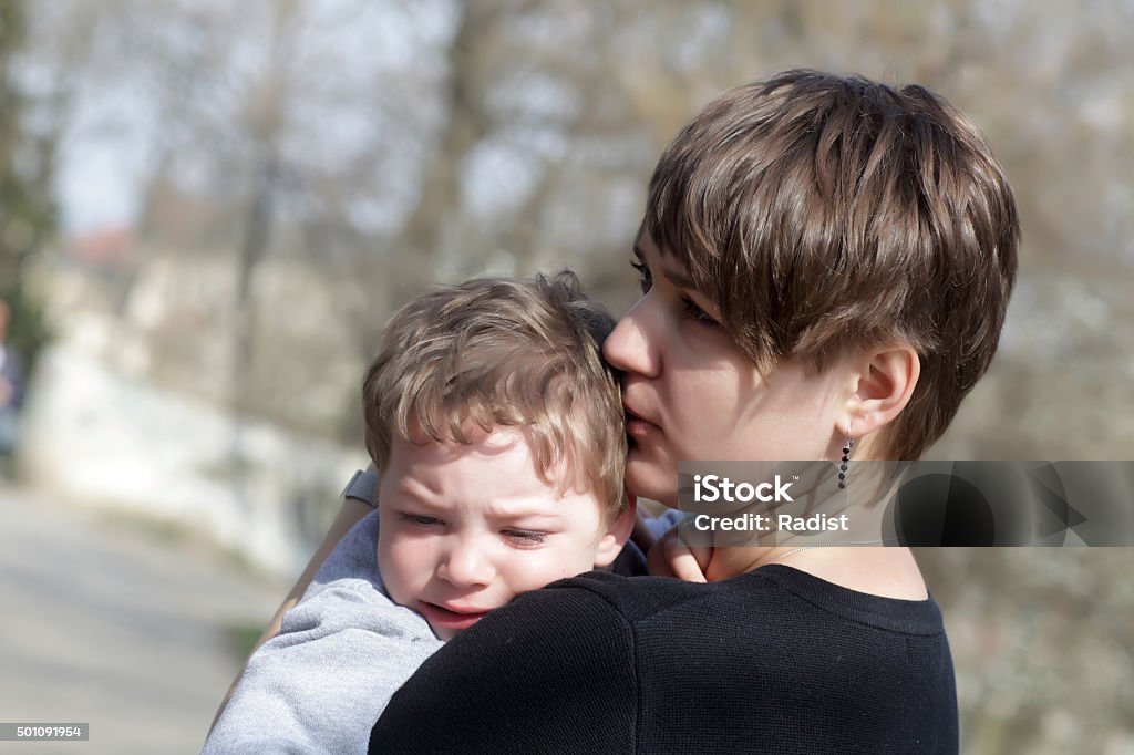 Mother hugging her crying son Mother hugging her crying son in the park Sadness Stock Photo