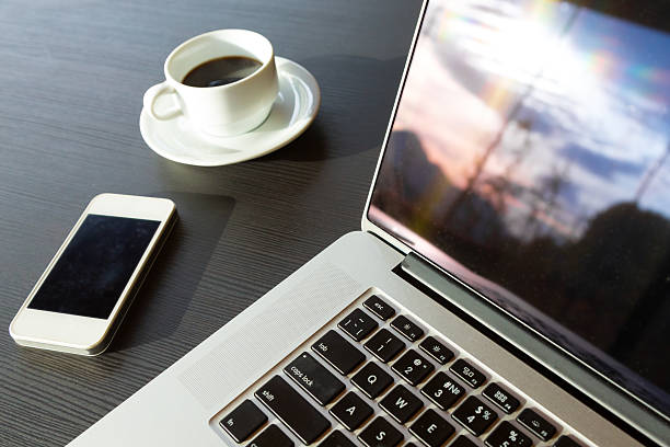 istock Laptop Telephone Coffee on black wood Table Nature view reflection 501092560