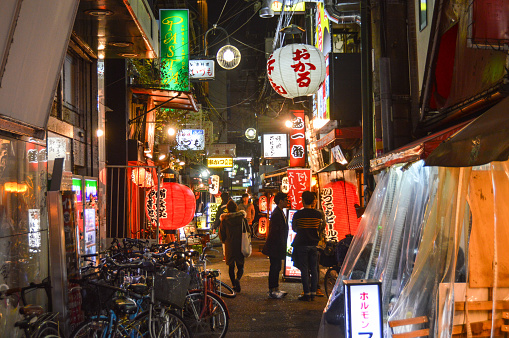 Osaka, Japan - November 27, 2015: Typical Osaka alleyway near the famous Dotonbori Canal. Photo features businesses and several people walking down the street.