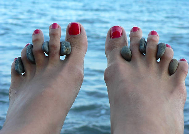 Female legs on sea procedures with curative stones between fingers