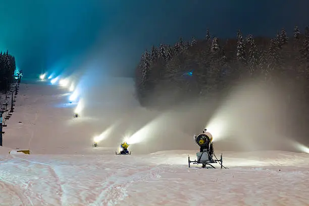 Photo of snow cannons working at night in the mountains