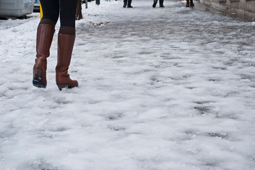 Woman with brown leather boots walks on icy street in Rome
