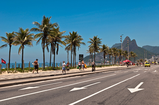 Rio de Janeiro, Brazil - November 21, 2013: Ipanema beach in the morning, view of the street, palm trees and mountains in the horizon.