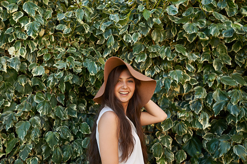 Cropped portrait of a pretty teenage girl standing in front of a large hedgehttp://195.154.178.81/DATA/i_collage/pi/shoots/783557.jpg