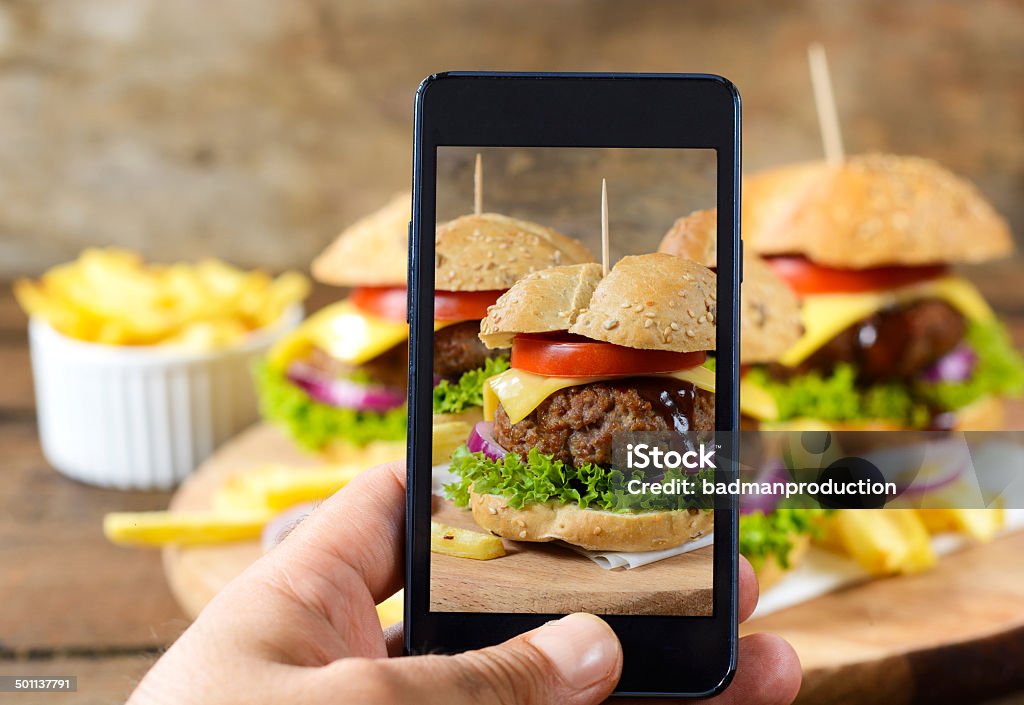 Mobile photography Man shooting with his cell phone camera big and tasy burgers.Selective focus on the phone Burger Stock Photo