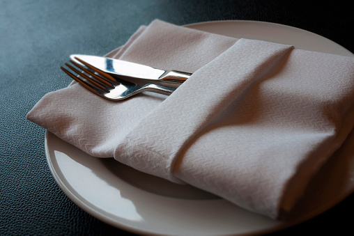 A soft toned image of a table setting with plate, napkin and utensils