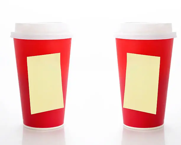 Coffee to go. Two paper coffee cups with blank yellow sticky notes