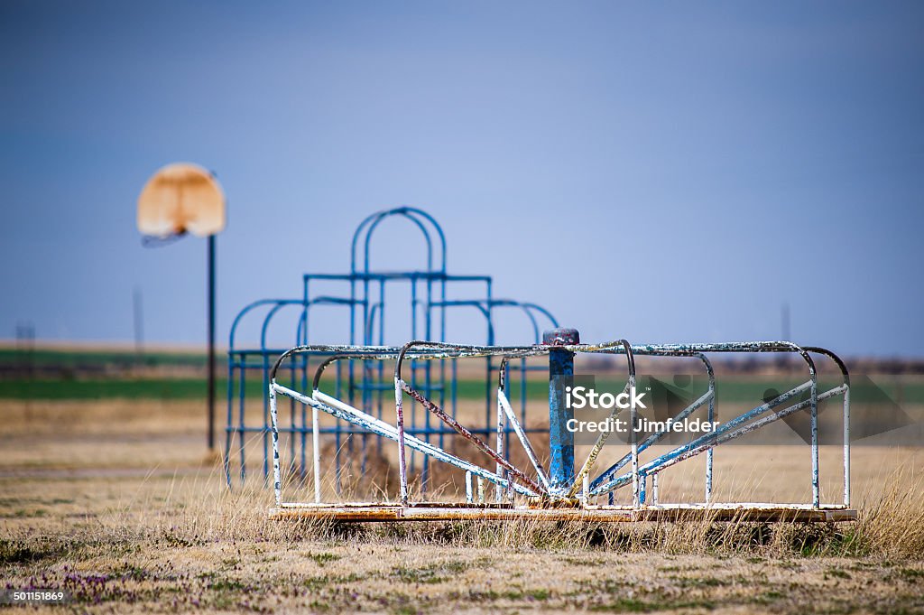 Abandoned Playground Toys Horizontal image of abandoned playground. Basketball goal, Monkey bars and Merry-Go-Round against blue sky. Abandoned Stock Photo