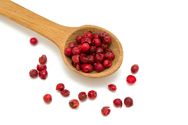 i grani di pepe rosa in un cucchiaio di legno - pink peppercorn foto e immagini stock