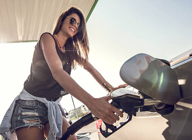 счастливая женщина в полёте газовая майка на топливный насос. - gasoline filling gas station car стоковые фото и изображения