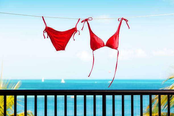 Red Bikini on Clothes Line Horizontal Subject: Red bikini swimsuit hanging and drying on a clothes line along the sea of the Caribbean Sea. swimwear bikini top bikini bikini bottom stock pictures, royalty-free photos & images