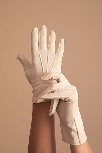 woman modeling vintage formal white knit gloves A woman's hands and forearms are shown as she models a vintage pair of formal white knit gloves. She seems to be adjusting the gloves. formal glove stock pictures, royalty-free photos & images
