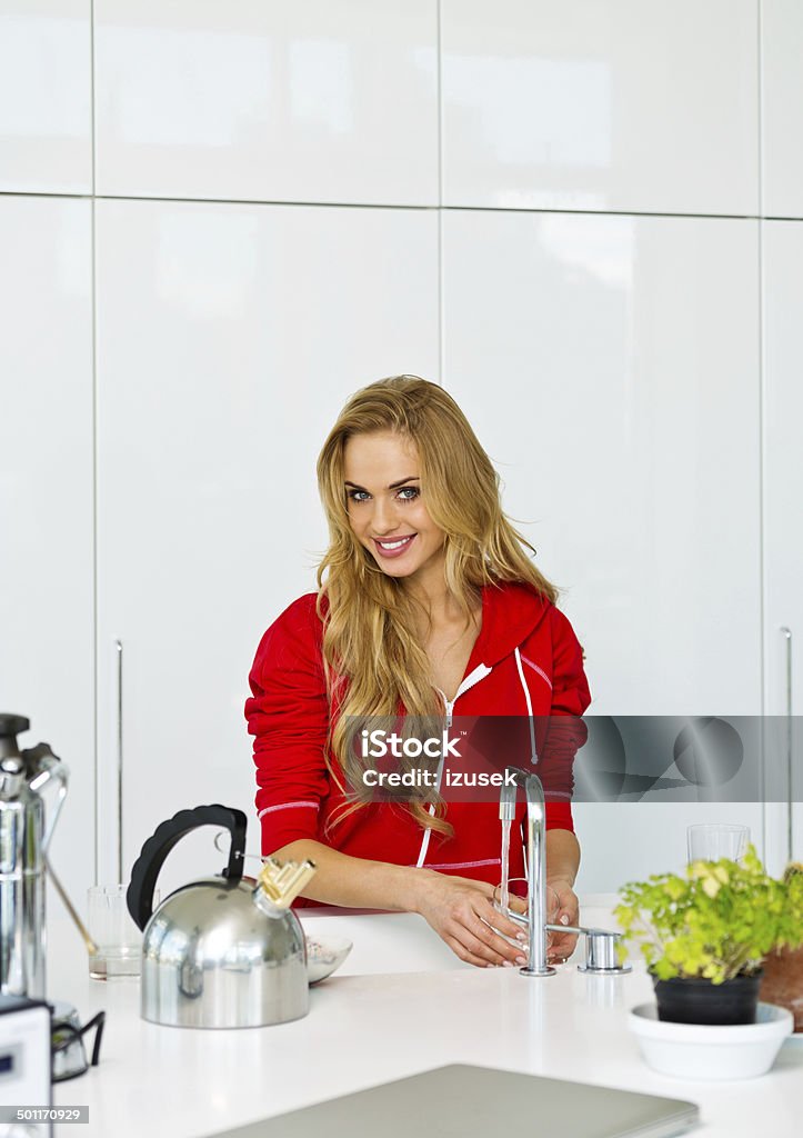 Young woman in the kitchen Young woman washing dishes in modern kitchen, smiling at the camera. 20-24 Years Stock Photo