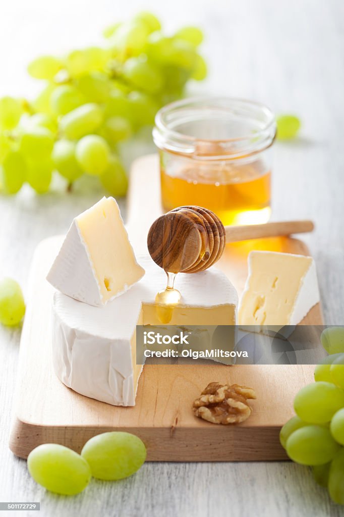 camembert cheese with grapes, honey and nuts on wooden backgroun camembert cheese with grapes, honey and nuts on wooden background Appetizer Stock Photo