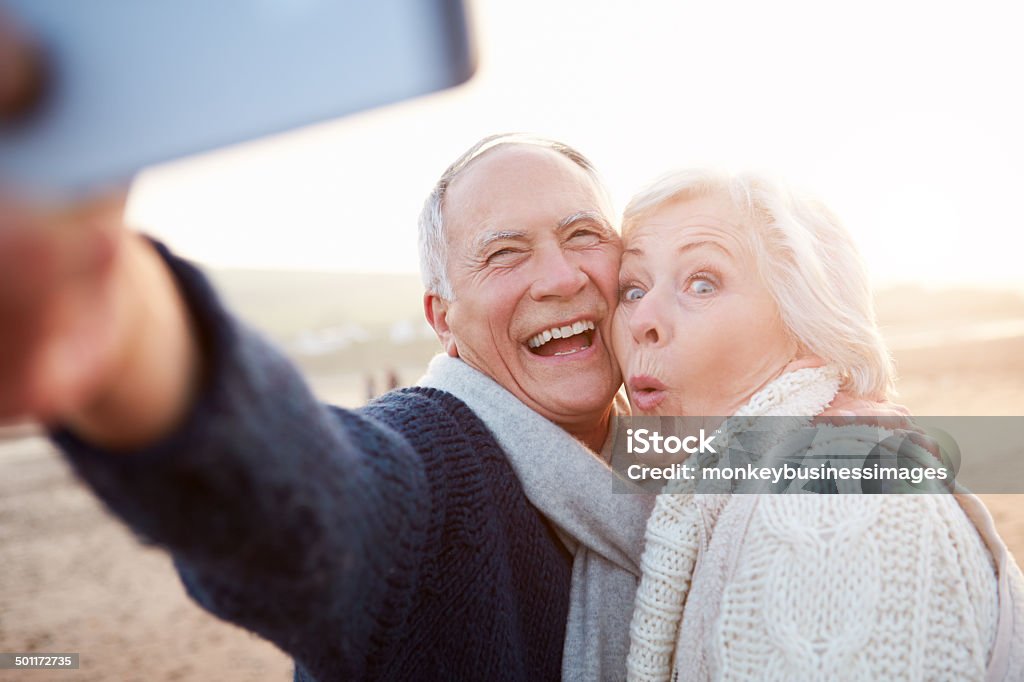 Coppia Senior in piedi sulla spiaggia e fanno Selfie - Foto stock royalty-free di Selfie