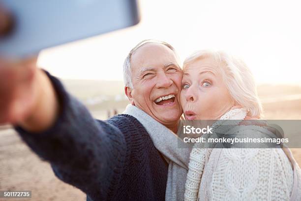 Senior Couple Standing On Beach Taking Selfie Stock Photo - Download Image Now - Selfie, Senior Men, 60-69 Years