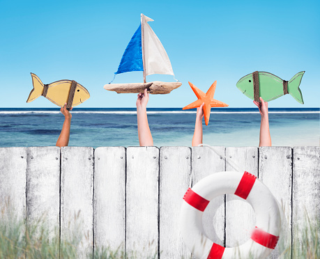 Beach and Wooden Plank Fence with Hands Holding Toys