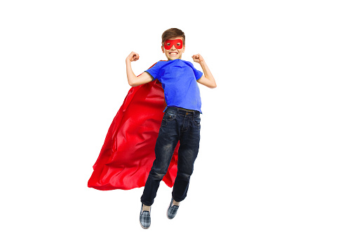 happiness, freedom, childhood, movement and people concept - boy in red super hero cape and mask flying in air