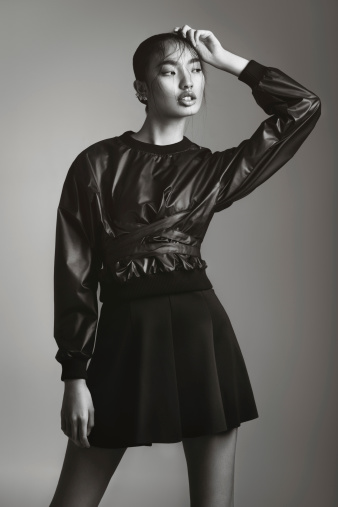 Portrait of asian fashionable woman wearing black leather top and skirt. Professional make-up and hairstyle.