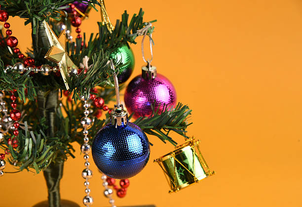 istock Decorated Christmas tree with colorful ornaments on yellow background 501192942
