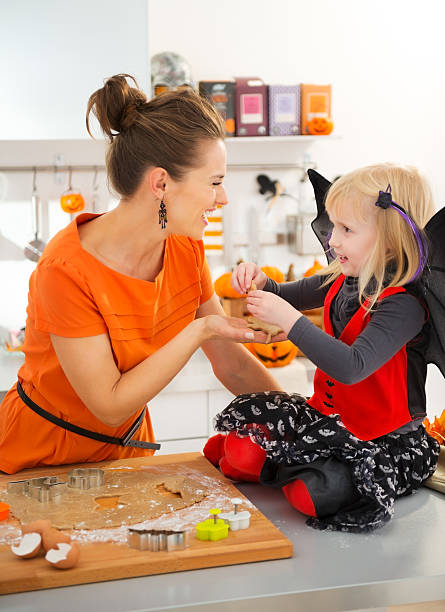 istock Halloween dressed girl with mother holding uncooked biscuits 501195662