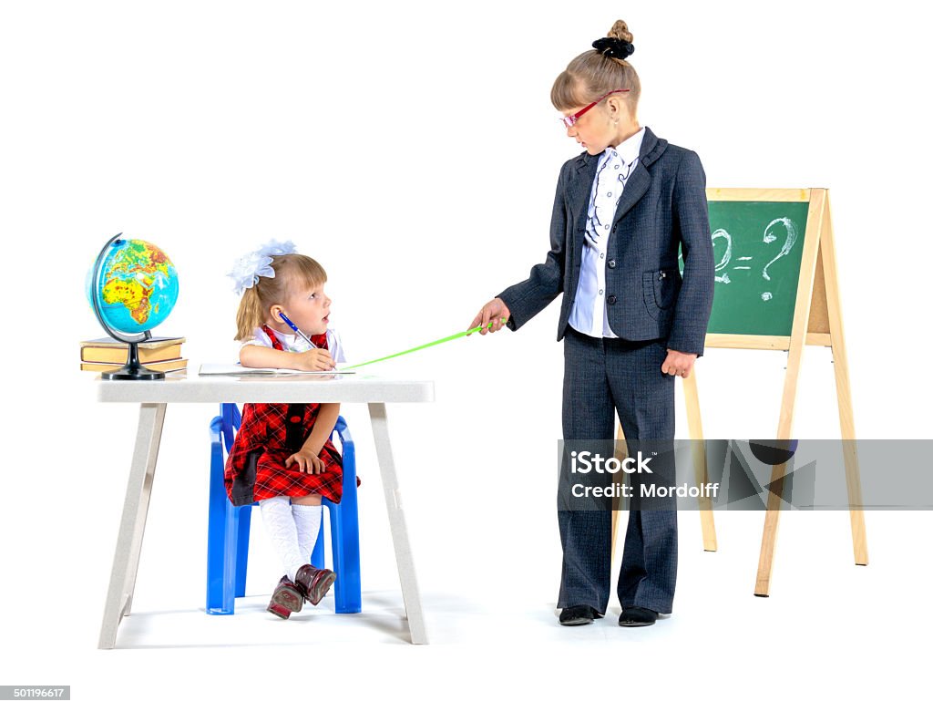 Playing lesson Two little girls playing school. One of the girls is teacher, the second girl is pupil. Isolated on white Chalkboard - Visual Aid Stock Photo