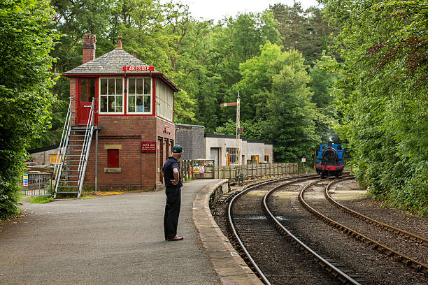 Train conductor at Lakeside and Haverthwaite Railway Haverthwaite, England - June 14, 2014 - Train conductor waiting for the train at Lakeside and Haverthwaite Railway, a steam railway located in the picturesque Leven Valley at the southern end of Windermere. grasmere stock pictures, royalty-free photos & images