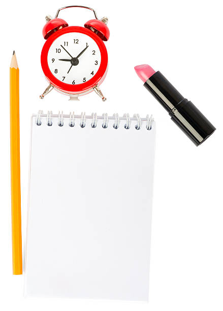 Open copybook with lipstick and alarm clock