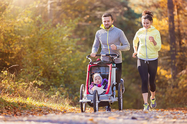Young family running Beautiful young family with baby in jogging stroller running outside in autumn nature pushchair stock pictures, royalty-free photos & images