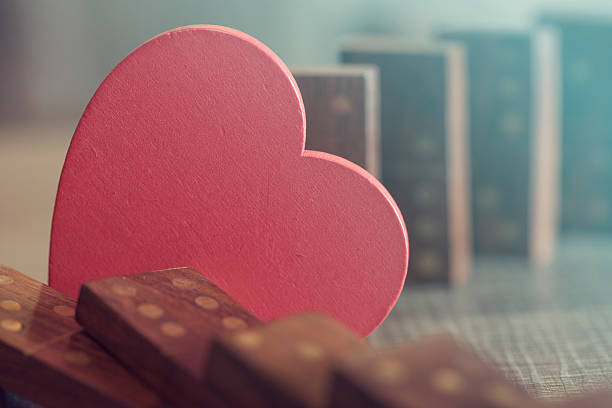 Love concept with heart stopping dominoes from falling. Selective focus image cross processed for vintage look