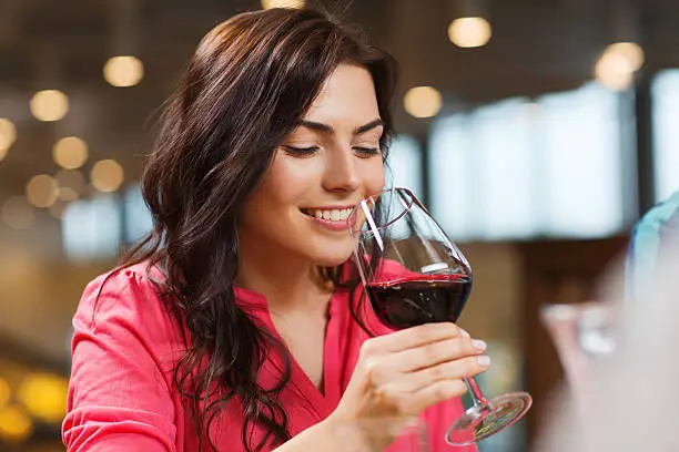 Photo of smiling woman drinking red wine at restaurant
