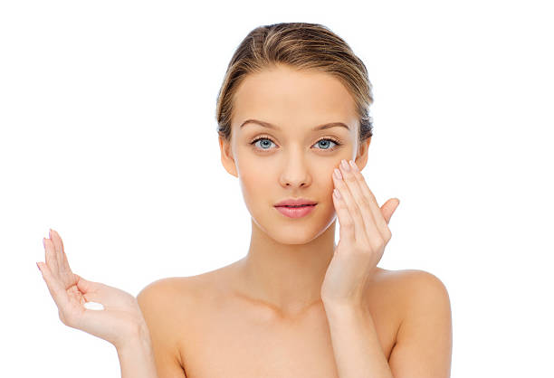 istock young woman applying cream to her face 501206364