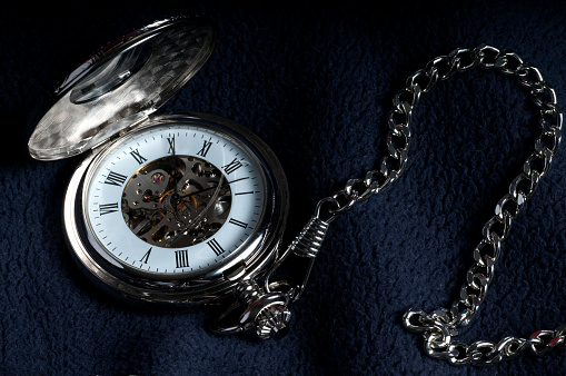 Antique pocket watch from 1917 with old U.S silver dollars on black background.