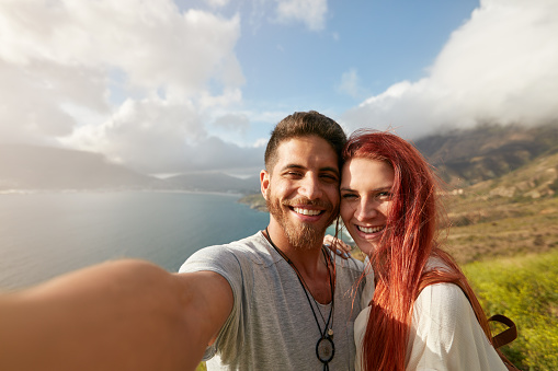 Cheerful young couple taking a selfie outdoors. POV shot man holding a camera taking a self portrait with his girlfriend.