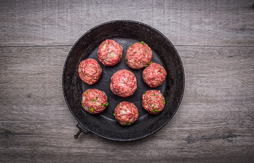 meat balls with herbs and onions in a vintage pan on wooden rustic background top view close up