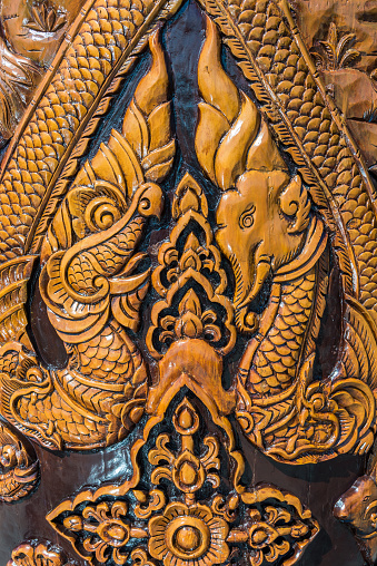 Old carved elephant and dragon on wooden pillars in the Thai temple.