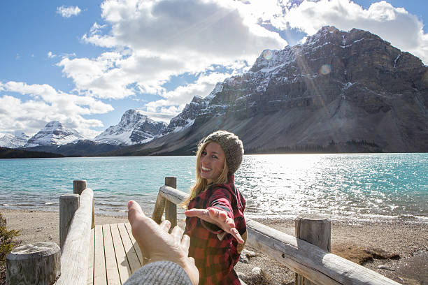 giovane donna che cammina sul ponte di registro uomo che tiene la mano - bow lake foto e immagini stock