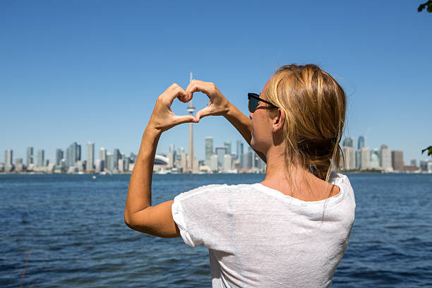 Young woman making heart shape frame to Toronto city