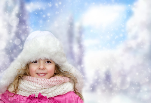 Happy smiling little child girl on snowy winter outdoor background with empty copy space.Beautiful laughing kiid wear hat, scarf in park.