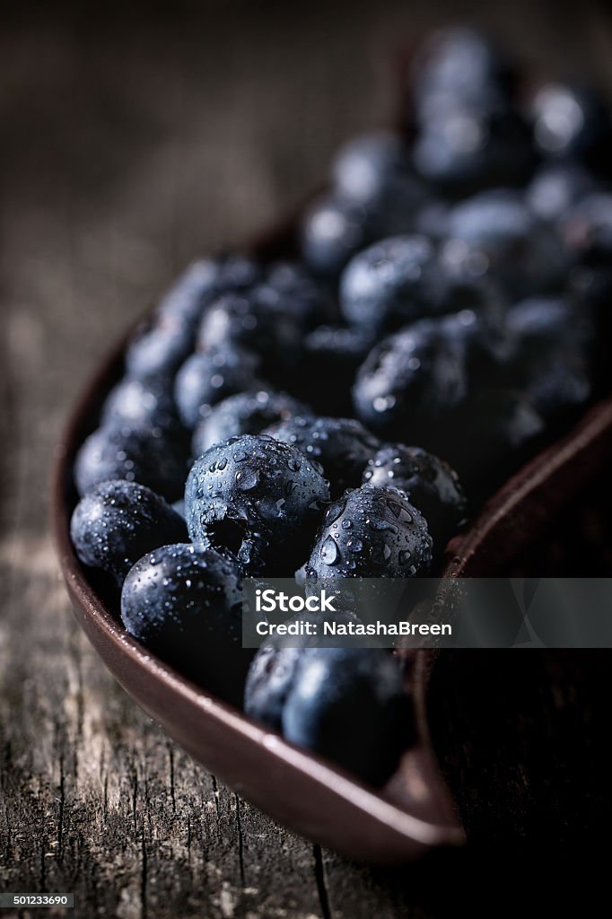 Close up of blueberries Close up of fresh wet blueberries in decorative ceramic plate over old wooden table 2015 Stock Photo