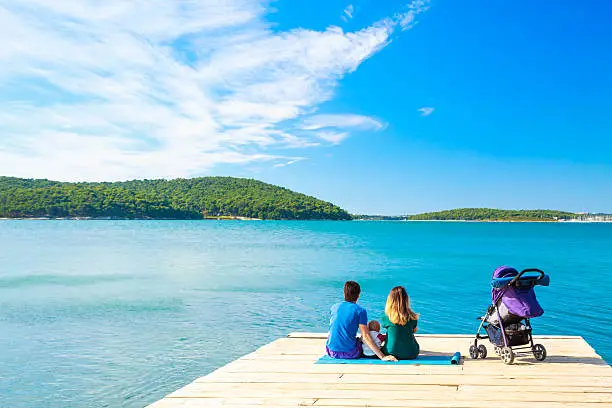 Photo of Family with Little Baby Sitting on Pier near the Sea