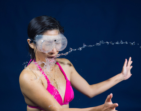 A young Asian girl catching water against a blue background