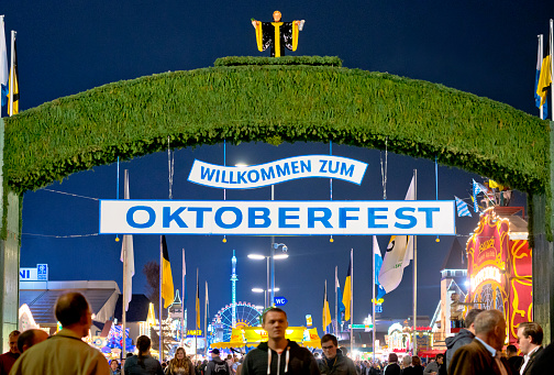 Munich, Germany - October 01, 2013: Welcome sign at Oktoberfest in Munich, Germany. Many People walking trough the entrance gate.  The annual event attracts almost 1 million visitors, who enjoy local beer, music, food and leisure activities.