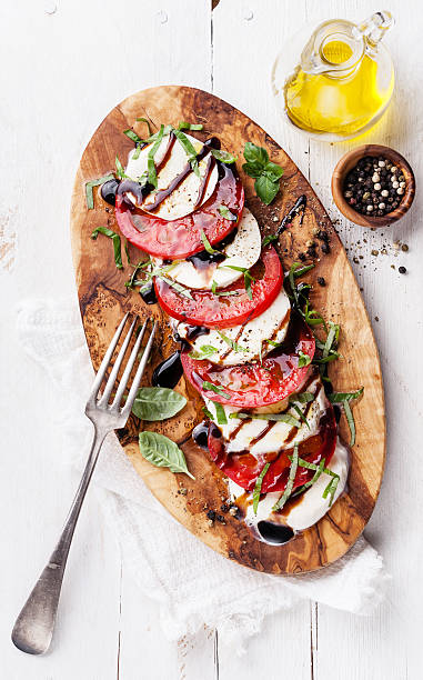 Caprese salad Caprese salad Tomato and mozzarella slices with basil leaves on olive wood cutting board caprese salad stock pictures, royalty-free photos & images