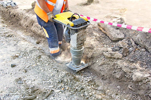 Compactor Worker uses compactor to firm soil at worksite compactor photos stock pictures, royalty-free photos & images